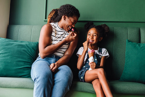 Happy mother and daughter enjoying ice cream on a couch