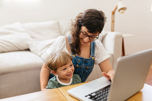 Happy mother and son with laptop at home