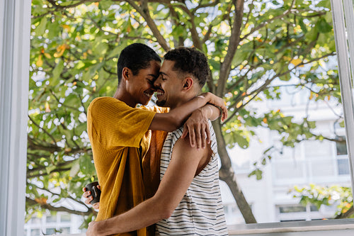 Loving couple embracing by a window in a bright natural setting