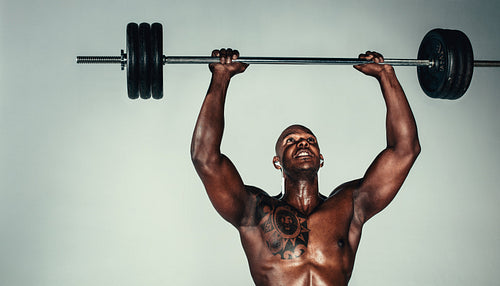 Muscular african man exercising with barbell