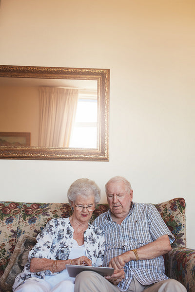 Retired couple at home using digital tablet