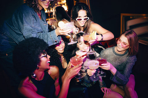 Group of friends toasting cocktails at a vibrant nightlife celebration
