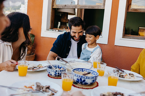 Family enjoying a cheerful moment during an outdoor Brazilian churrasco meal