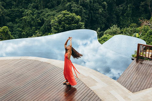Beautiful young woman dancing near swimming pool