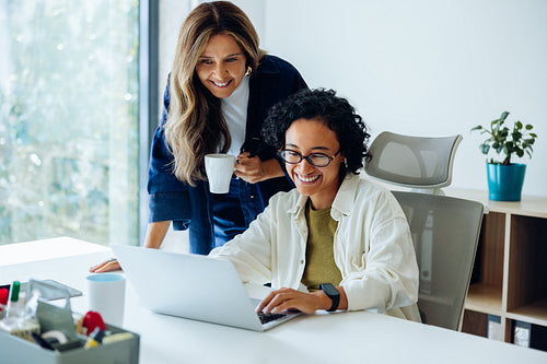 Two women at work share a laptop and ideas