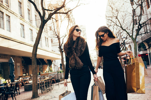 Friends walking on the city street with shopping bags