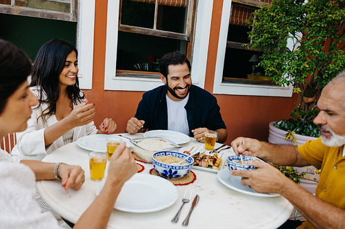 Family gathering enjoying a meal outdoors around a cozy dining setting
