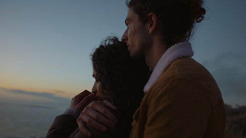 Romantic couple together admiring the sunset over sea