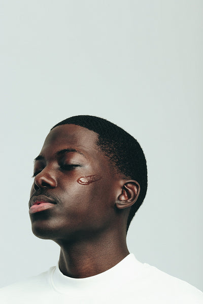 Face serum on melanin skin: Youthful black man practicing a healthy skincare routine