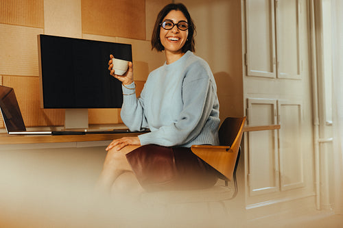 Woman takes a coffee break at her desk in a bright office workspace