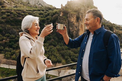 Happy senior couple making a toast while hiking outdoors