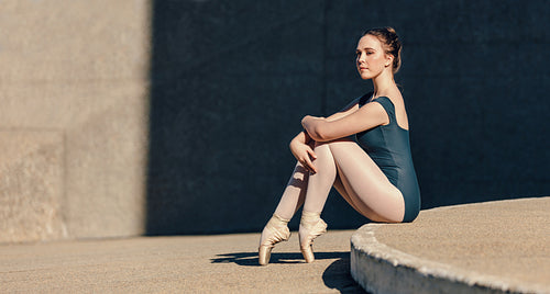 Female ballet dancer sitting gracefully while resting her toes on the ground
