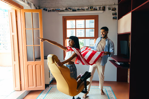 Happy father and daughter playing together indoors with creative imagination