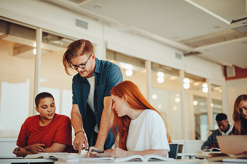 Male teacher assisting teenage students in the classroom