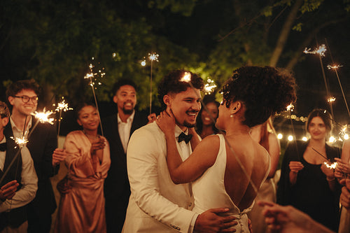 Romantic wedding dance with sparklers surrounded by joyful guests at night