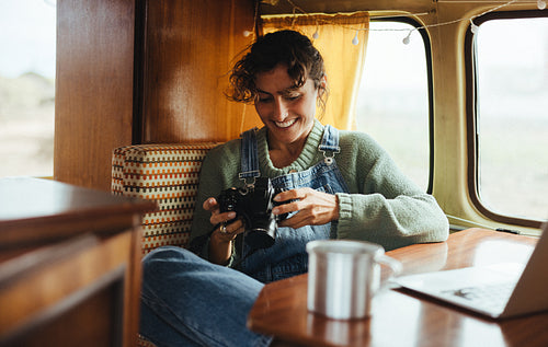 Photographer inside vintage camper, smiling while reviewing camera