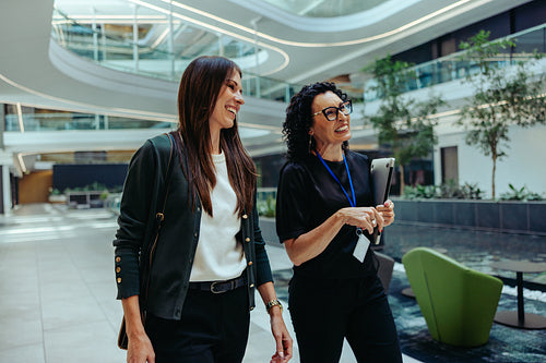 Two female coworkers walking through a modern office space