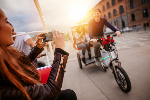Woman photographing friends on tricycle ride.