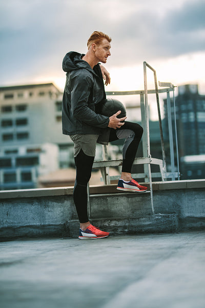 Man standing on terrace of a building holding a medicine ball