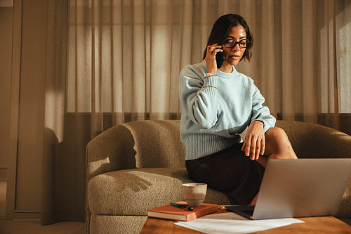 Woman works on a laptop while talking on the phone in a private office