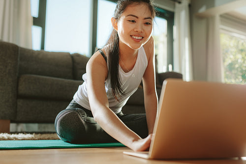 Woman using laptop while exercising at home