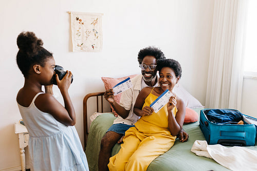 Mature parents getting photographed by daughter's camera, posing for a picture with travel tickets
