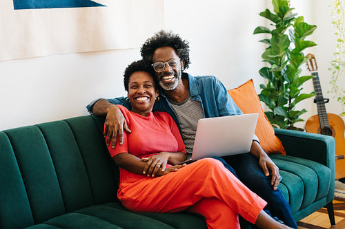 Mature couple enjoying quality time at home, hugging and smiling on the couch