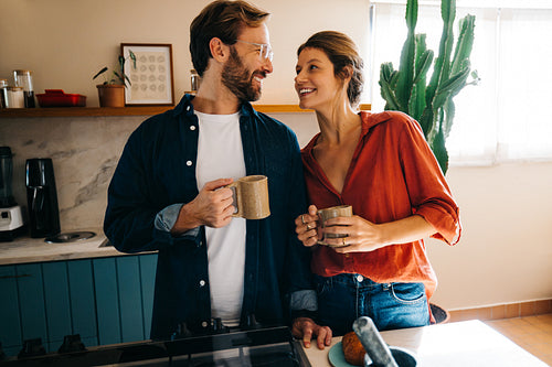 Couple sharing coffee and smiles in cozy sunlit kitchen