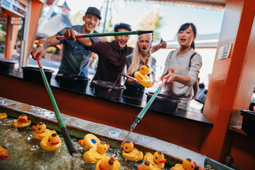 Group of people playing fishing game at amusement park
