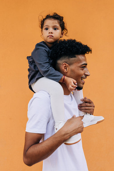 Single dad carrying his daughter on his shoulders in a studio