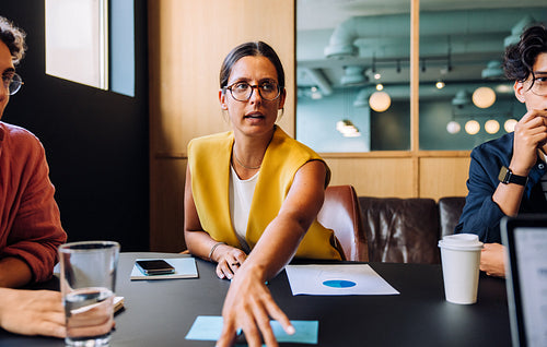 Woman demonstrating and discussing documents with colleagues in a professional meeting