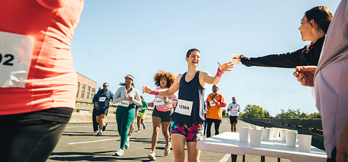 Female runner reaching for water at race hydration point