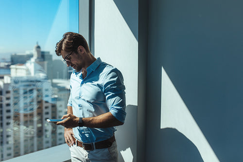 Business investor standing by a window in office.