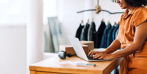 Happy online store owner using a laptop in her shop
