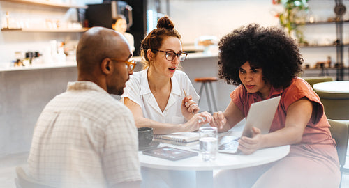 Group of remote workers brainstorming with a laptop in a coffee shop