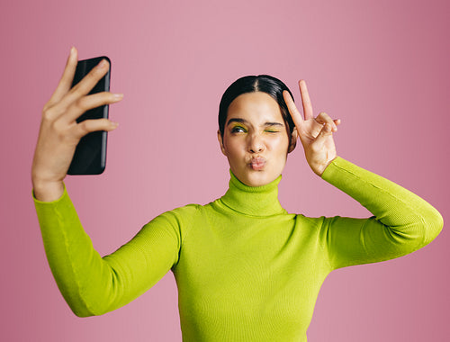 Glamorous generation: Vibrant young woman taking selfies and capturing her colourful style
