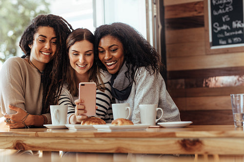 Friends sitting in a cafe looking at mobile phone