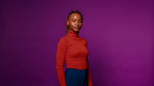 Confident black woman in studio portrait with purple backdrop