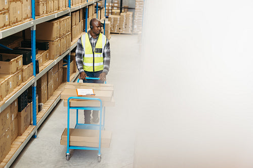 Black warehouse worker batch picking with a headset on
