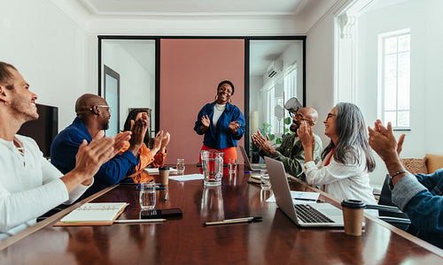 Team applauds during business presentation in modern office boardroom