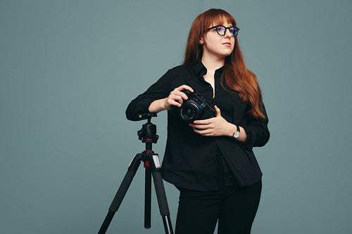 Photographer standing next to her tripod in a studio