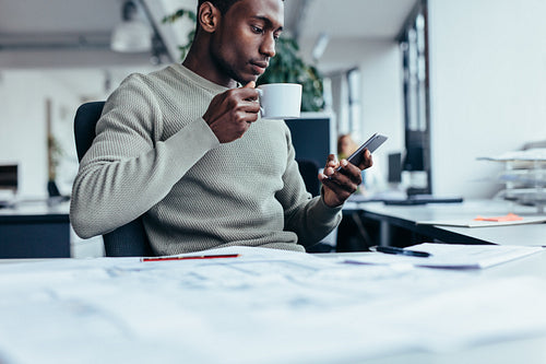 Businessman sitting at office desk having a coffee