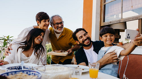 Smiling family enjoying a churrasco meal together outdoors on a sunny day