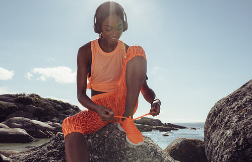 Woman tying her shoe laces before a run at beach