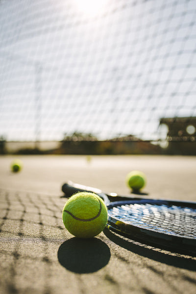 Close up of a tennis racket and balls lying on a court