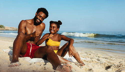 Father and daughter playing in the sand on a sunny beach