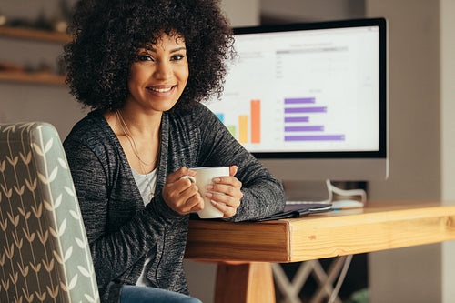 African woman at her work desk with cup of coffee