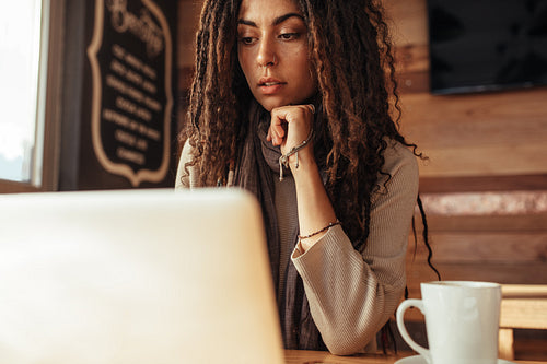 Woman entrepreneur working on laptop computer in a cafe