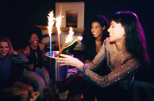 Group of friends celebrating with sparkler candles and champagne at a party