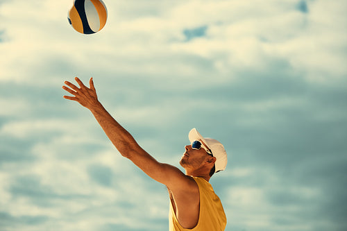 Male athlete spiking yellow volleyball on beach during championship game